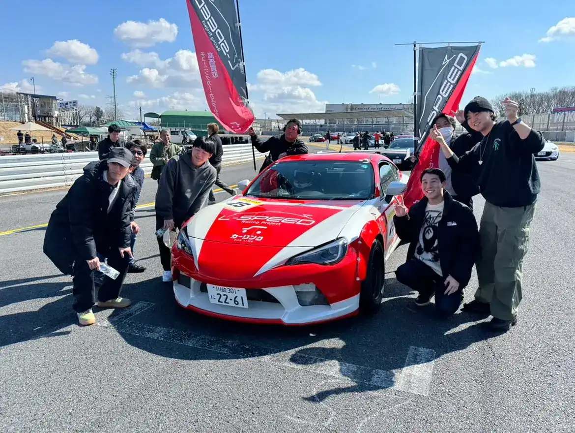 サーキットでL-SPEEDのレース車両を囲むスタッフ